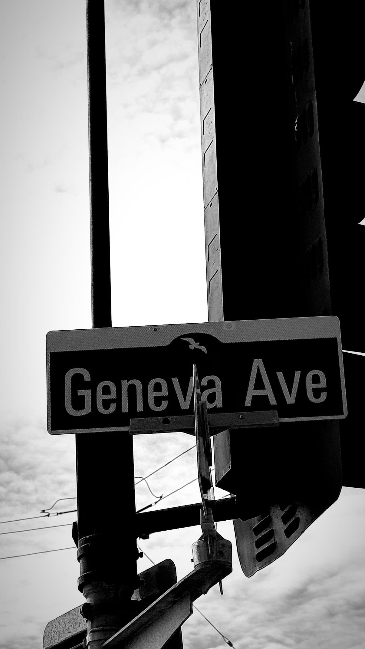 Geneva Ave: a street sign tilted against the sky, in black and white