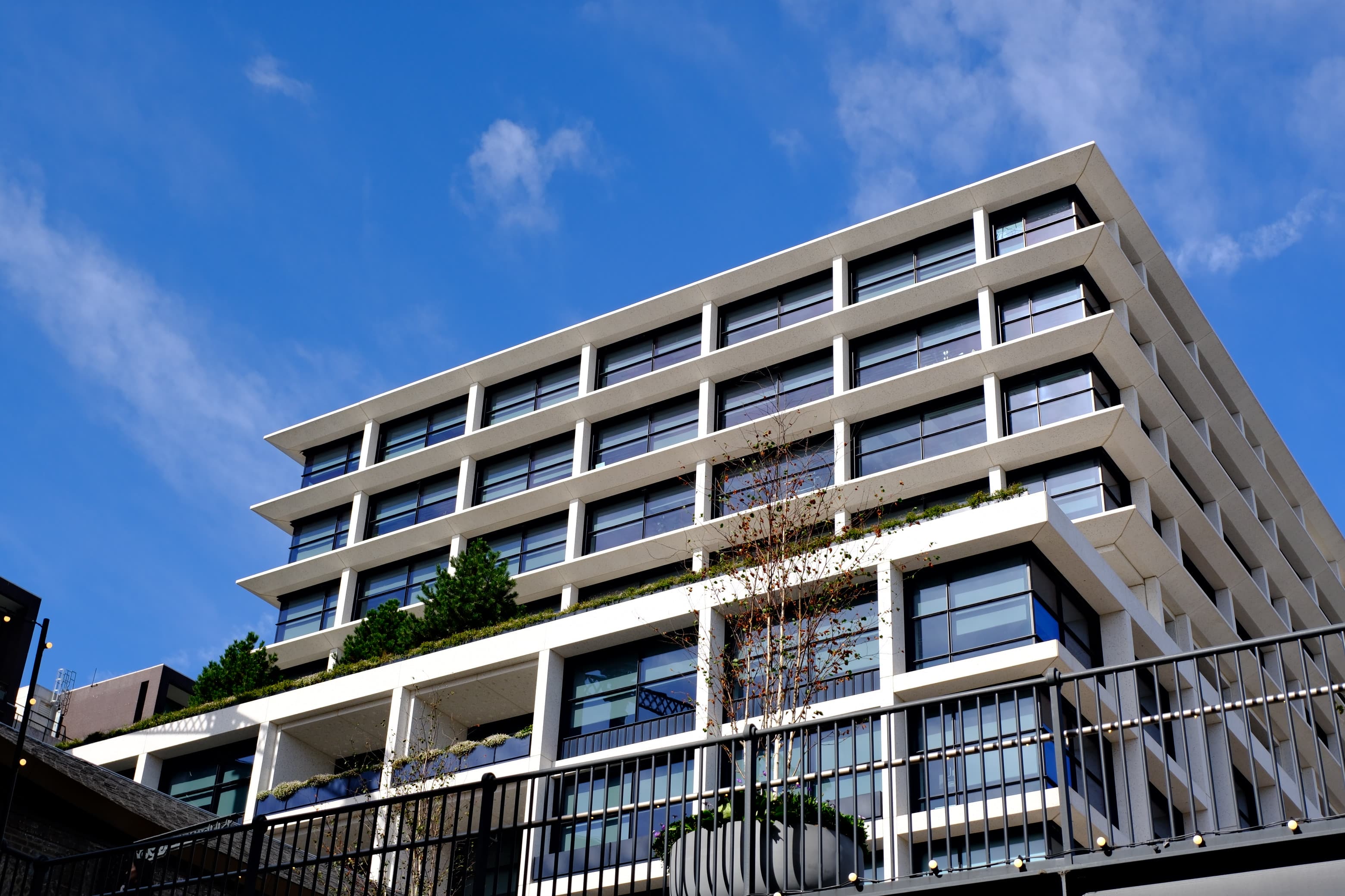 A white modernist office building with deep window frames against a bright blue sky